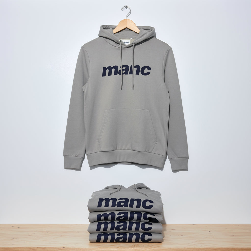 Grey manc hoodie on a wooden hanger with more on a wooden shelf below it.