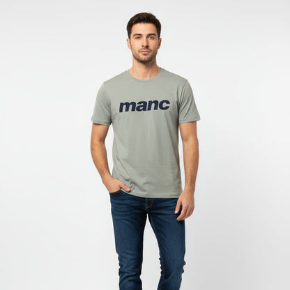 Man wearing a grey manc t-shirt with  blue jeans on a white background