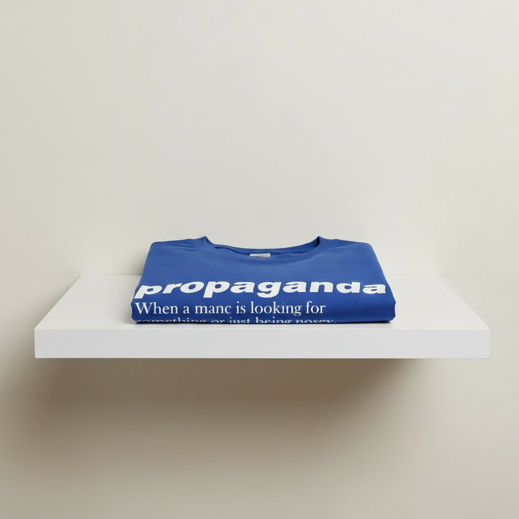 Blue t-shirt with 'propaganda' text on a white shelf
