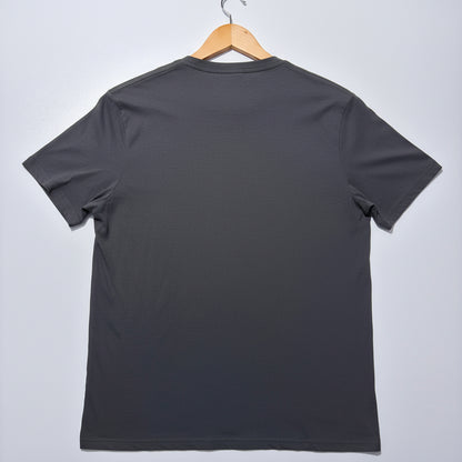 Grey t-shirt on a wooden hanger against a light grey background