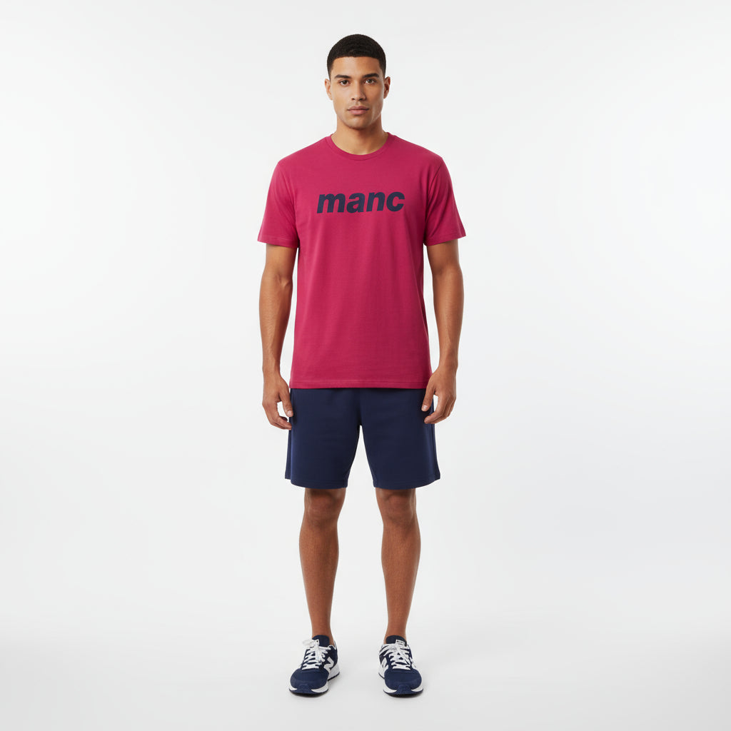 Man wearing a red manc t-shirt and navy shorts on a white background