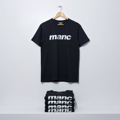 Black t-shirt with 'manc' text in reflective vinyl on a hanger against a white background