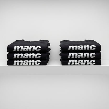 Stacks of black t-shirts with 'manc' printed on them against a white background