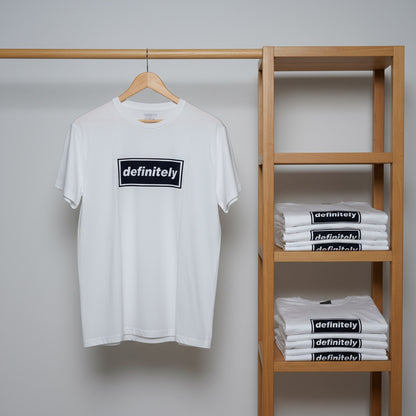 White t-shirt with 'definitely' print on a hanger and wooden shelf with folded shirts.