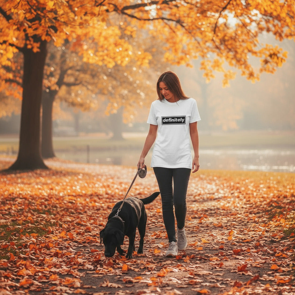 Woman walking a dog in an autumn park with trees and fallen leaves.