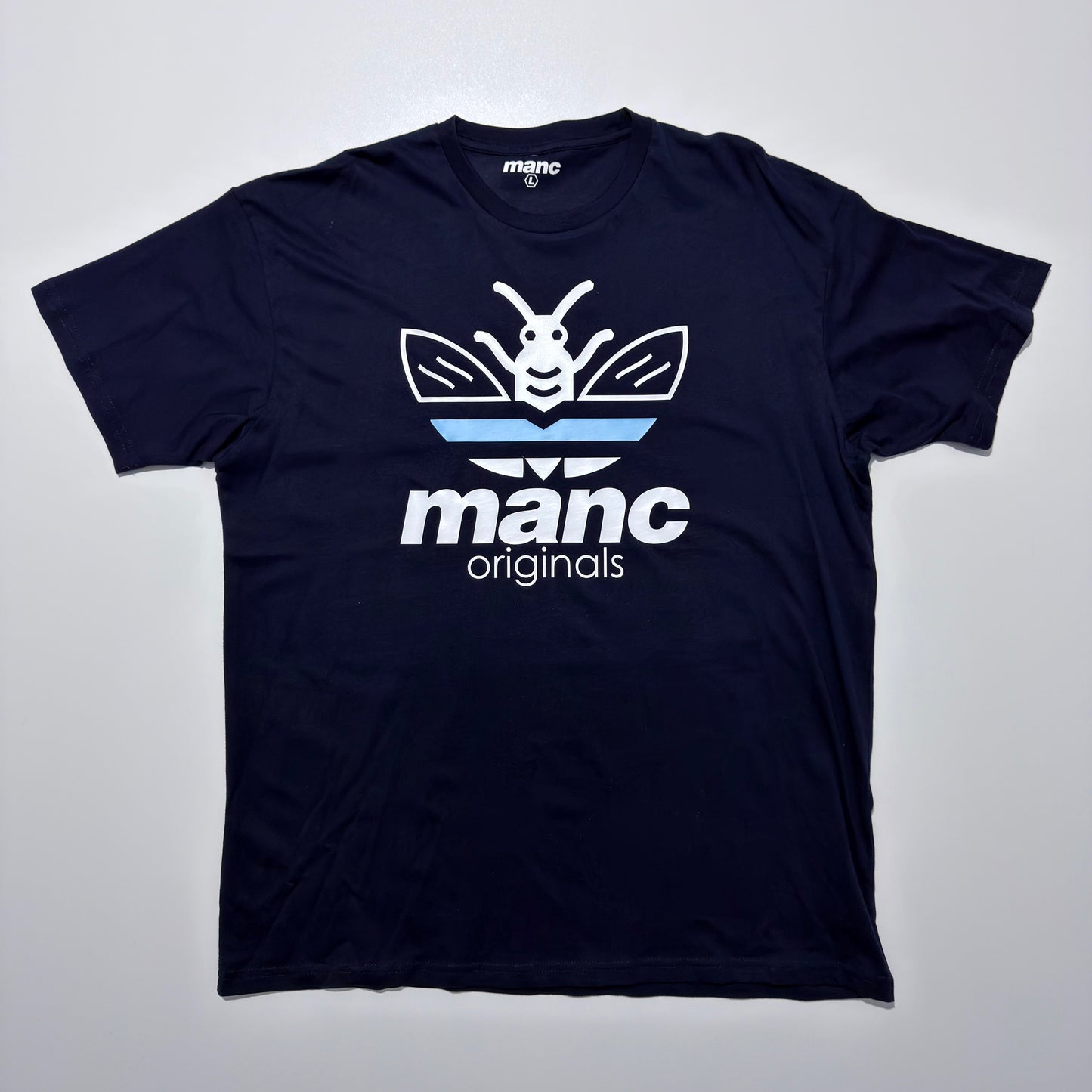 Navy blue t-shirt with 'manc originals' logo on a light grey background