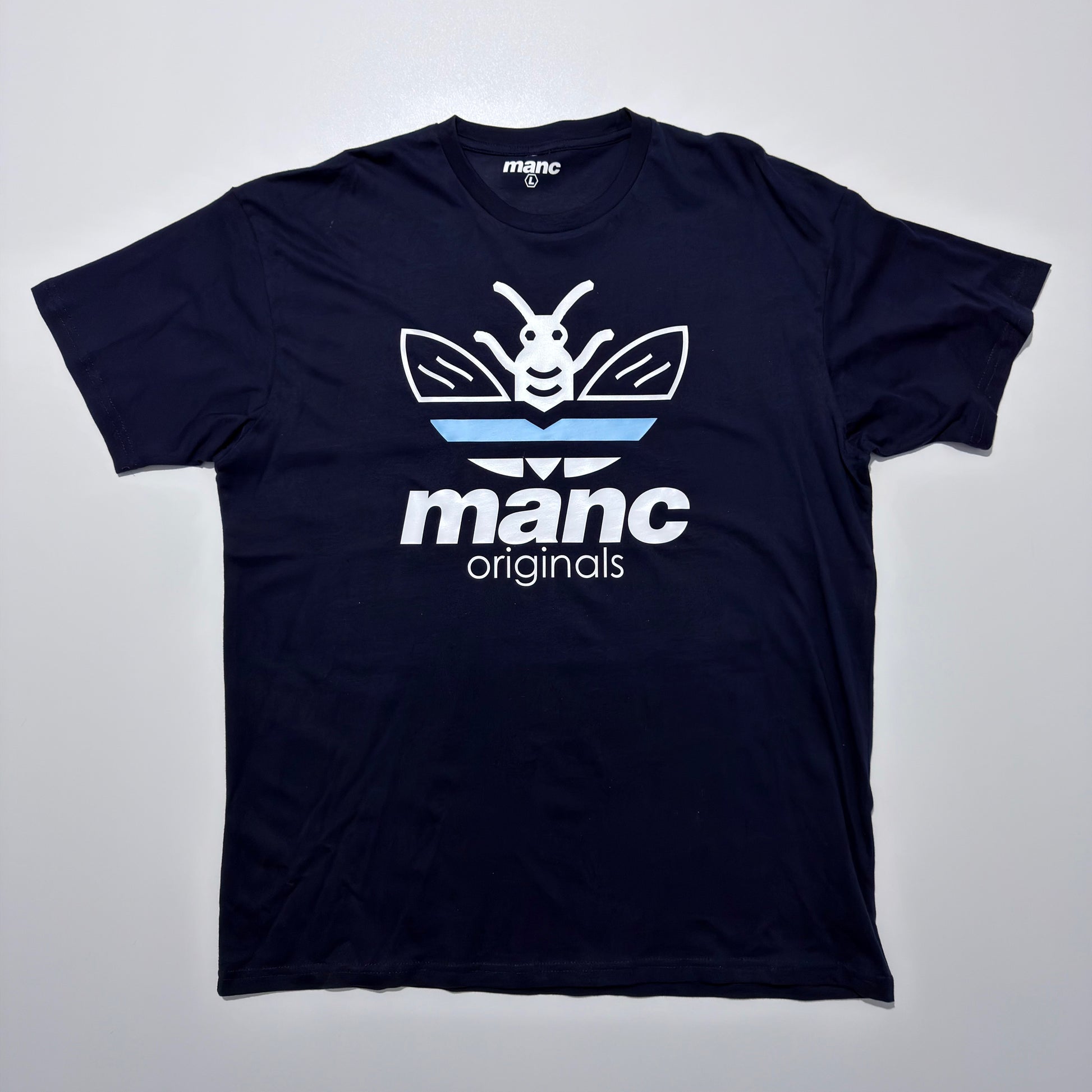 Navy blue t-shirt with 'manc originals' logo on a light grey background