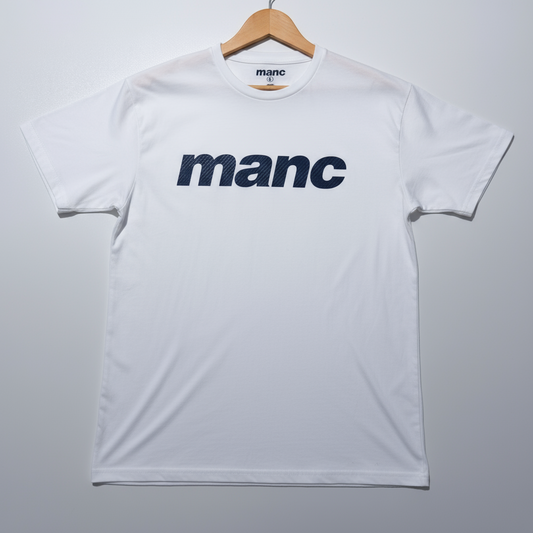 White manc t-shirt, hanging on a wooden hanger against a grey background.